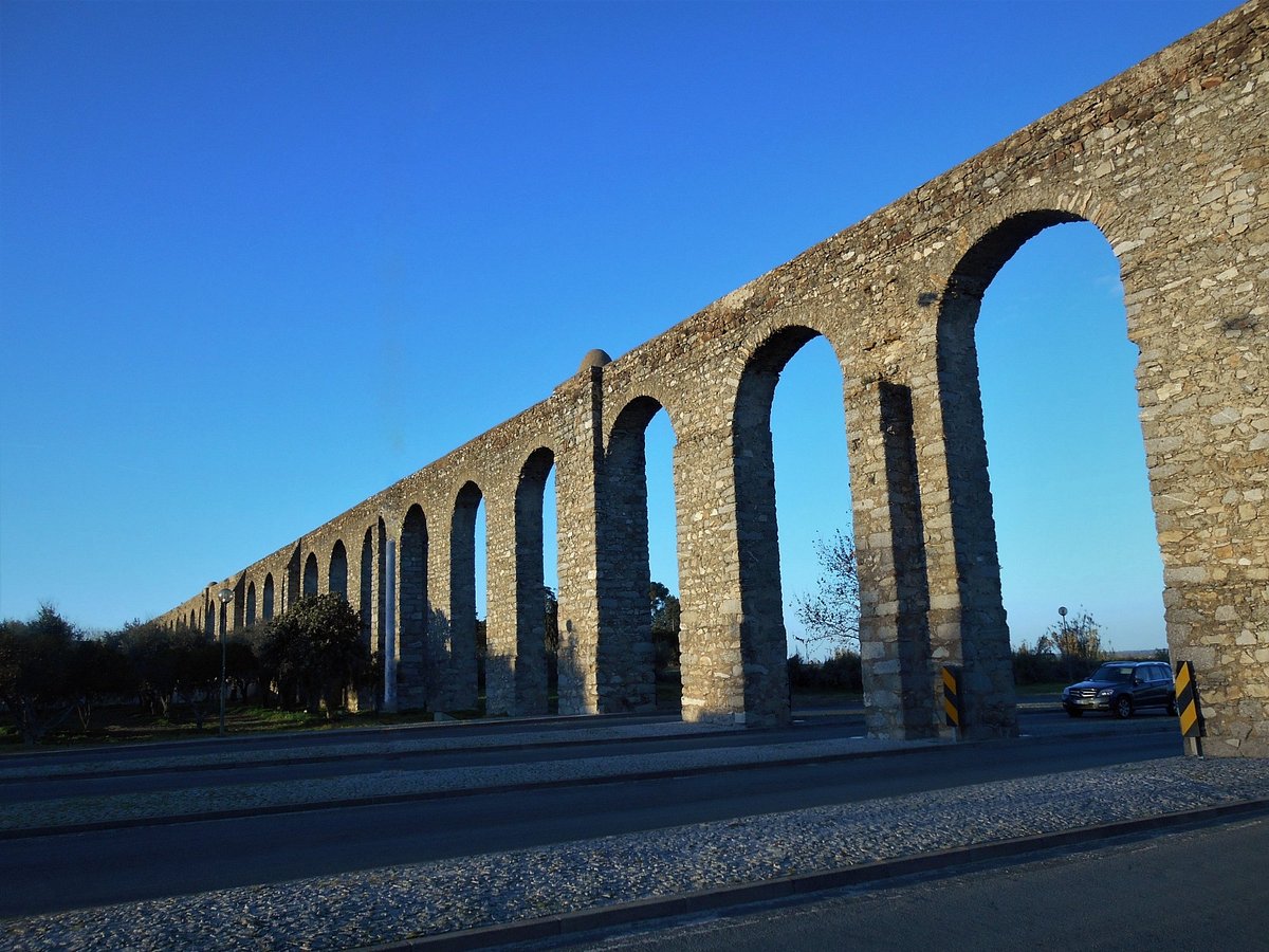 Aqueduto da Água de Prata in Évora, a 16th-century aqueduct built by King João III with arches blending into the cityscape, featured in the Lisbon to Évora Private Wine & Culture Tour by Lux Motion.